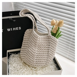 Detailed macro view of the hand-woven hollow knit pattern on a beige beach tote bag