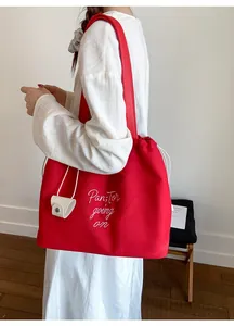 Detail of red canvas tote bag with drawstring closure and white accessory pouch