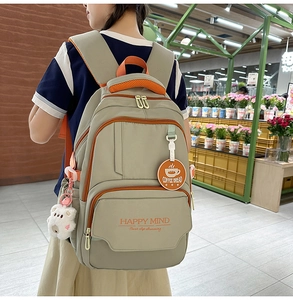 Detail view of khaki school backpack with orange trim and cute plush bear accessory