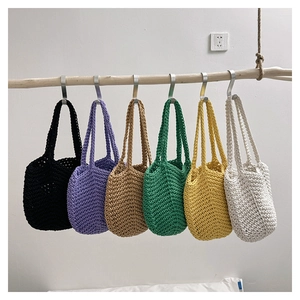 Detail shot of multi-color handmade crochet tote bags hanging on a rustic wooden pole