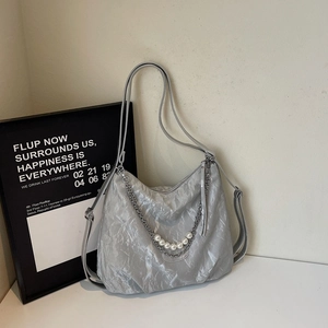 Detail of silver-grey tote bag with metallic texture, pearl chain and silver accents