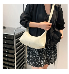 Detail of creamy white crescent bag with lychee grain leather and vertical stitching