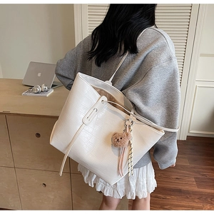 Detailansicht der weißen Tasche mit Krokoprägung und braunem Teddybär-Anhänger