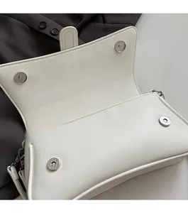 Detail view of the white leather shoulder bag showing the secure double magnetic clasp closure