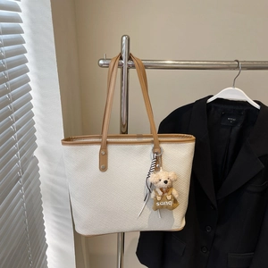 Détail du cabas en toile crème avec bordure marron et charmant pendentif d'ours en peluche