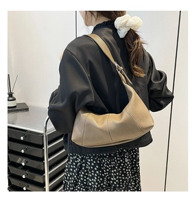 Detail view of coffee-colored baguette bag with lychee texture on woman shoulder