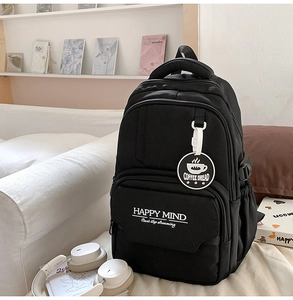 Close-up of black casual backpack with Happy Mind print and side pocket on a sofa