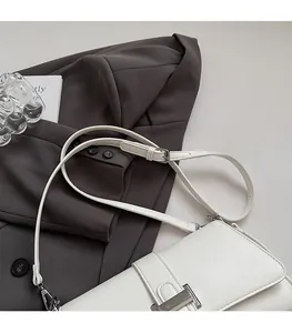Close-up of the adjustable strap and silver metal buckle on white minimalist handbag