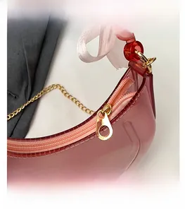 Detail view of pink translucent bag with smooth zipper, bead handle and silk ribbon