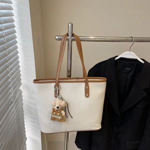Gros plan d'un grand sac cabas tissé avec bordure en cuir et charmant porte-clés ours