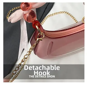 Detail of pink jelly crescent bag featuring gold chain strap and detachable lobster clasp