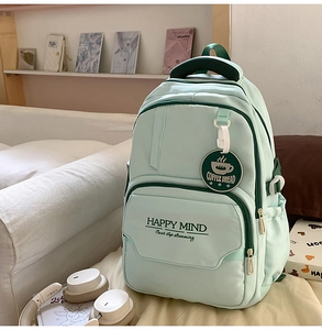Detail of mint green school backpack with Happy Mind print and decorative pendant charm