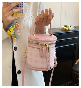 Close-up of pink checkered cylindrical bucket bag with gold hardware and zipper