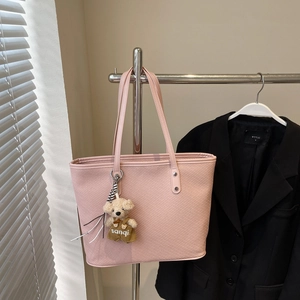 Texture détaillée du sac cabas tissé rose avec un charmant ours en peluche sur un cintre