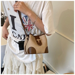Chic canvas and brown leather bucket bag shown in a stylish lifestyle outdoor setting