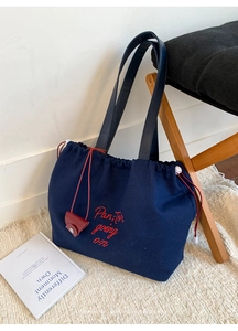 Detail of dark blue canvas tote bag with red embroidery and small red coin purse charm