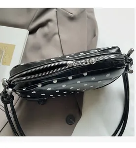 Detailed macro view of the smooth silver metal zipper on the black polka dot shoulder bag