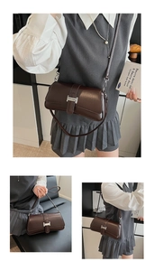 Detail view of dark brown faux leather bag with silver H-shaped buckle and straps