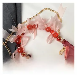 Detail of pink translucent jelly bag with red beaded handle and organza ribbon bow decoration