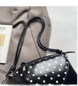 Close-up of black polka dot shoulder bag with silver metal accents on a blazer background