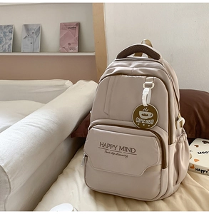 Detail of beige canvas backpack with multi-pockets and HAPPY MIND print and pendant