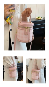 Detail of pink checkered cylinder bucket bag with gold zippers and adjustable strap