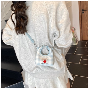 Detail of mini blue checkered bucket bag with cute dog patch and ruffle edge on strap