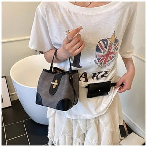 Detail of grey fabric bucket bag with black leather trim and golden metal twist lock