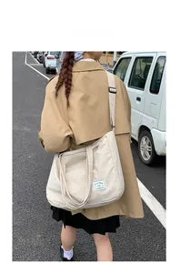 Model wearing a large cream canvas crossbody tote bag showing street style aesthetics