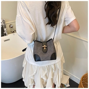 Detail of contrast bucket bag with suede fabric and gold lock shown on model