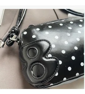 Detail of black polka dot bag with glossy finish and 3D number 8 leather patch