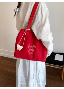 Detail view of red canvas tote bag with white letter embroidery and drawstring