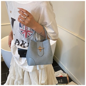 Close-up of light blue bucket bag featuring a gold twist lock and smooth leather texture