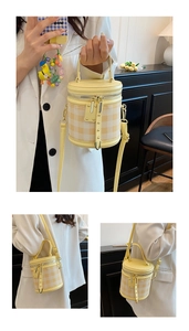 Detail view of the yellow plaid cylinder bucket bag with a cartoon duck charm and gold hardware