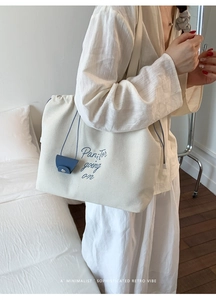 Detail of canvas tote bag with blue drawstring and matching small leather pouch accessory