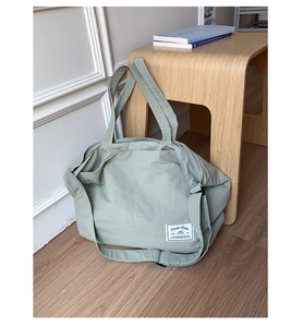Detail of light green waterproof nylon tote bag with adjustable strap and brand woven label