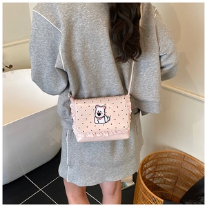 Detail of a pink polka dot crossbody bag with a cartoon dog patch and ruffled edges