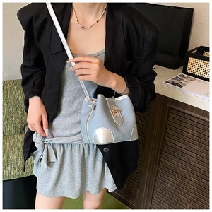 Detail of light blue canvas bucket bag with silver leather trim and gold lock