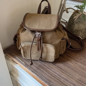 Detail of vintage canvas backpack showing buckle closure, drawstring, and leather trim