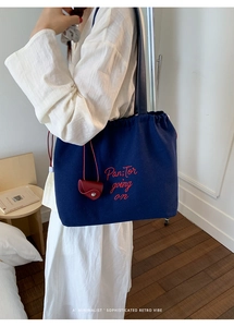 Close-up of navy canvas tote bag with red embroidery detail and leather charm