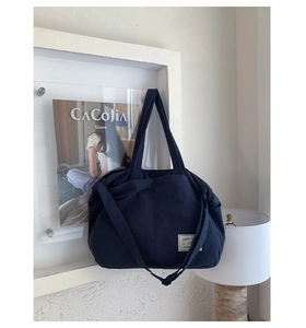 Detailed view of navy blue canvas tote bag featuring an adjustable strap and woven label