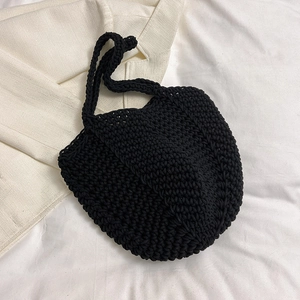 Detailed view of black hand-knitted tote bag with intricate crochet texture and round handles
