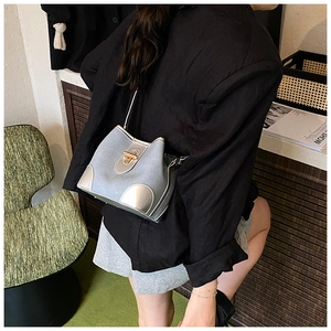 Detail view of silver-grey bucket bag with metallic trim and gold twist-lock closure