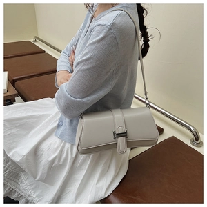Detail view of light grey minimalist underarm bag with silver buckle on a shoulder strap