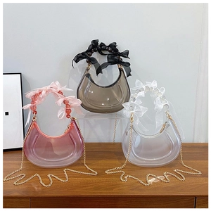 Three colors of transparent crescent bags with beaded handles and bow ribbons on a table