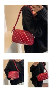 Detail of red patent leather shoulder bag with white polka dots and heart embossed design