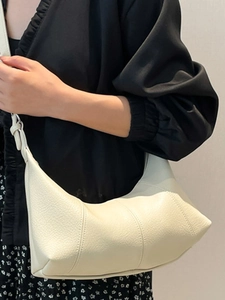Chic cream leather baguette bag with vertical stitching shown on model shoulder