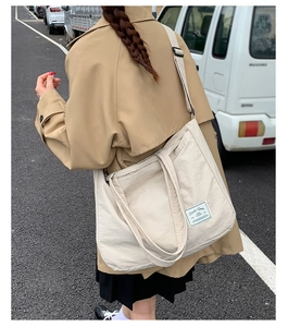 Detail of beige canvas tote bag showing adjustable strap and Everyday YOUNG label in outdoor setting