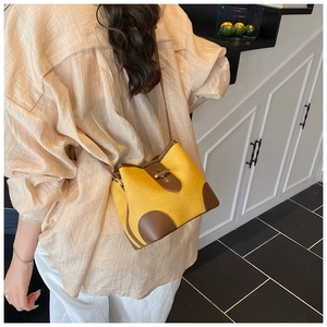 Fashionable bicolor bucket bag with brown leather trim and golden metal clasp on model