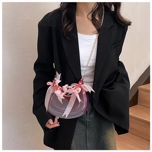 Detail of crescent crossbody bag with pink silk bows and red bead accents on metal chain